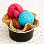 Three scoops of colorful ice cream — bright pink, blue, and chocolate — served in a waffle bowl with rainbow sprinkles, placed on a sprinkle-covered white background.