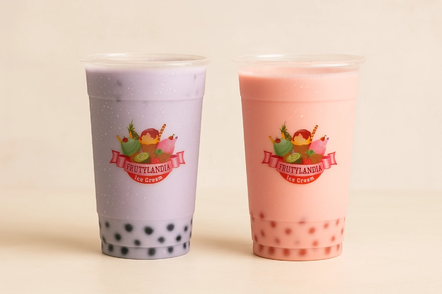 Two pastel-colored bubble teas from Frutylandia, one purple with black tapioca pearls and one pink with red pearls, in clear cups.